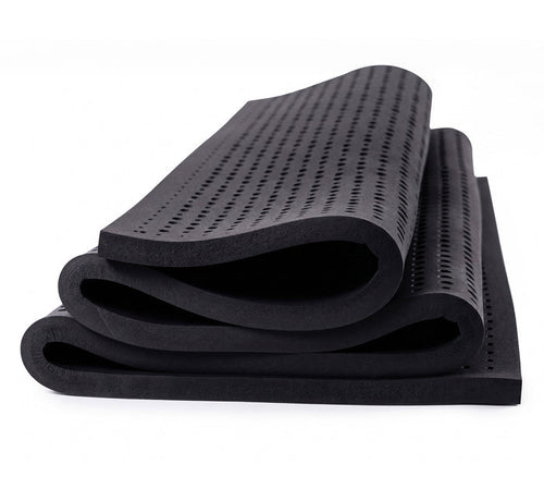 Turmerry Graphite Infused Latex Topper rolled and folded showing perforated dark gray surface with soft edges.