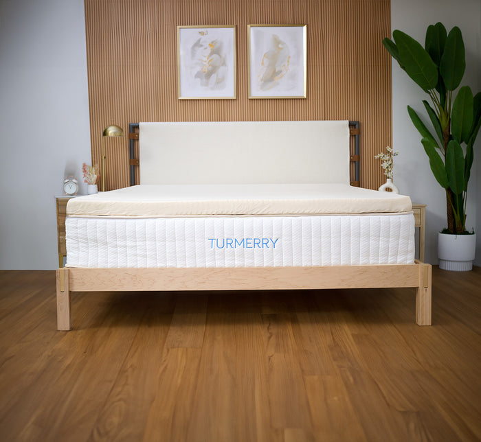 Turmerry Organic Latex Mattress Topper with cover on a Turmerry mattress on wooden bed frame in bedroom setting.