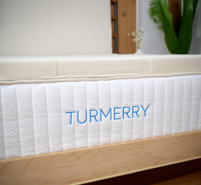 Front view of Turmerry Organic Latex Mattress Topper on a Turmerry mattress, showing embossed brand name on topper.