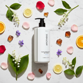 Apotheke Canvas hotel bath gel 480ml flat lay on white marble with lily of the valley rose violet citrus peach amber scent elements — luxury plant-based body wash