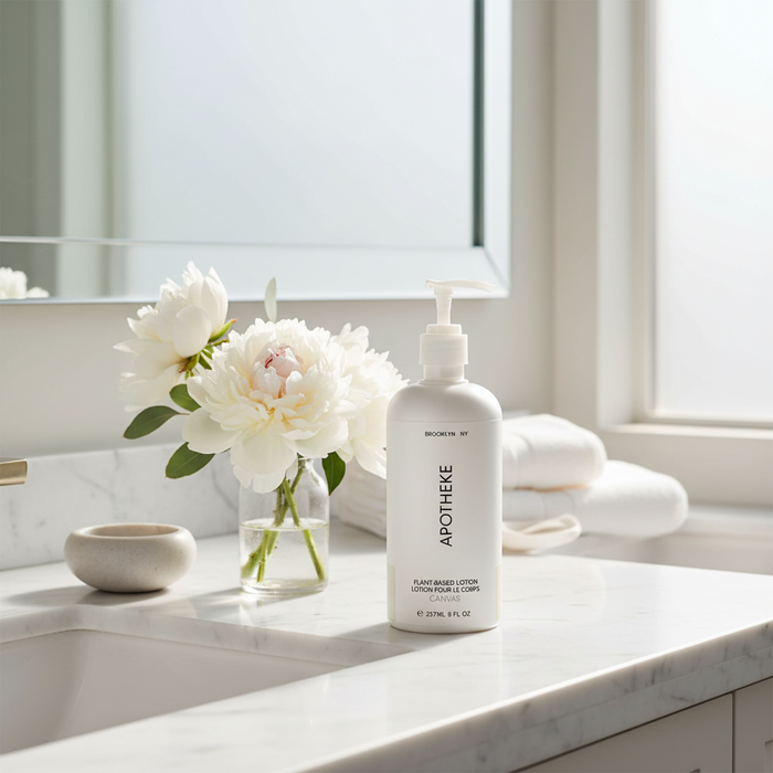 Apotheke Canvas Body Lotion on marble bathroom vanity with fresh white flowers — luxury home spa lotion hotel quality moisturizer
