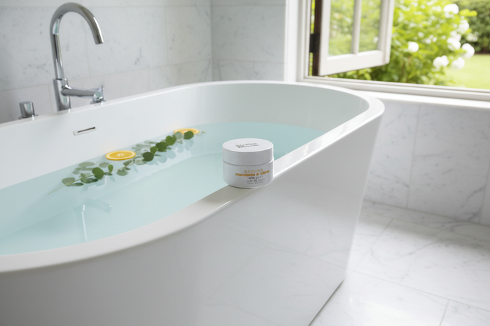 Atelier Bloem Bath Salts on edge of freestanding soaking tub with garden view