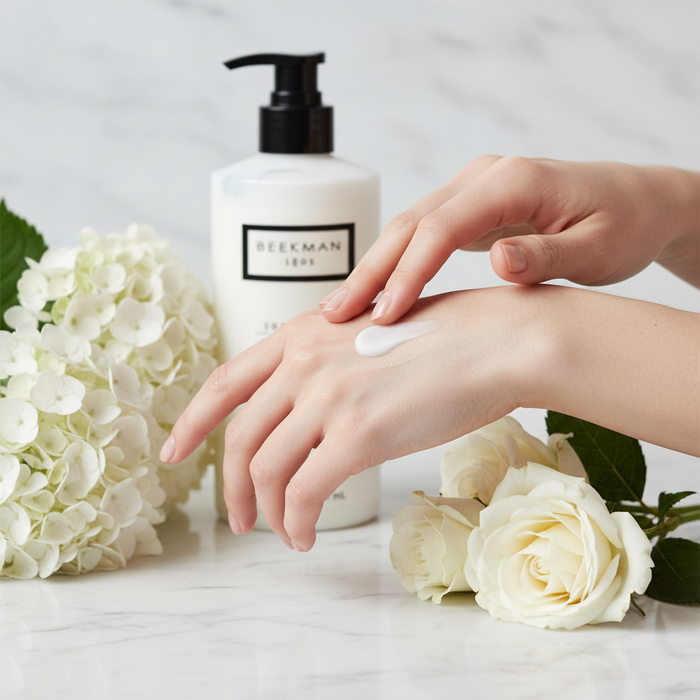 Beekman 1802 Fresh Air Body Lotion beauty shot hands applying lotion with white flowers - premium goat milk skincare moisturizer