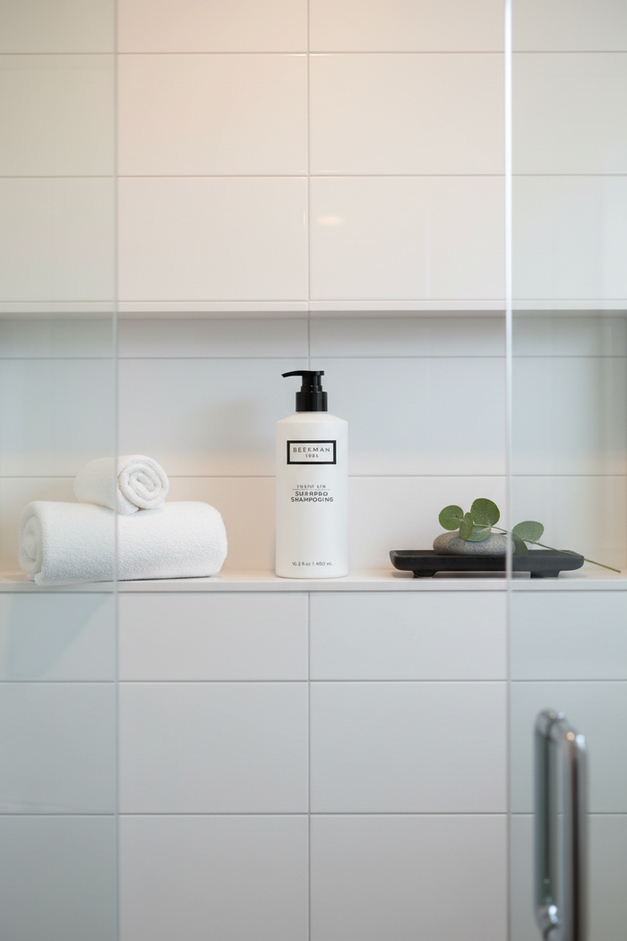 Beekman 1802 Fresh Air Shampoo white bottle black pump on spa shower shelf white tiles soft towels - premium goat milk shampoo