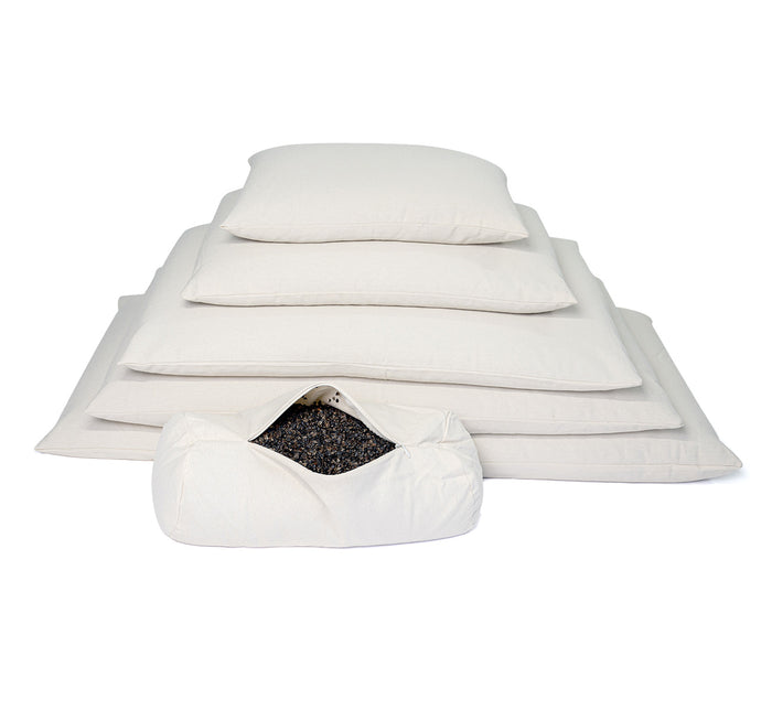 Circular Turmerry Buckwheat pillow with open cover showing hulls inside, with 5 stacked buckwheat pillows behind it.