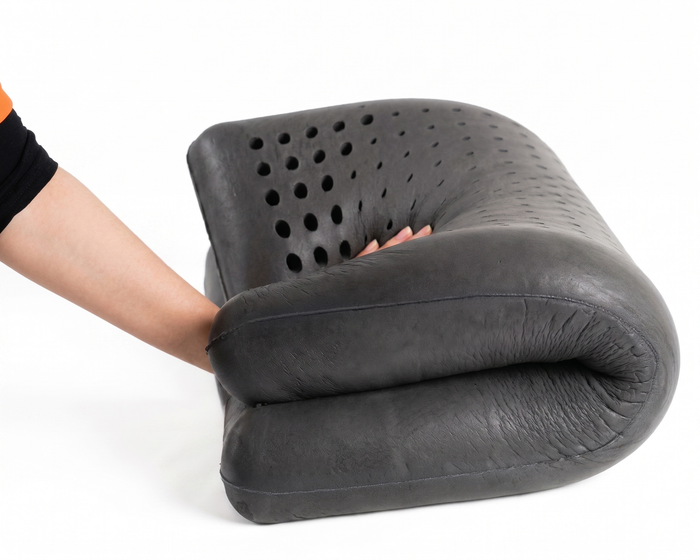 Hand pressing into folded Turmerry Cooling Graphite Latex Pillow, with perforated surface visible.