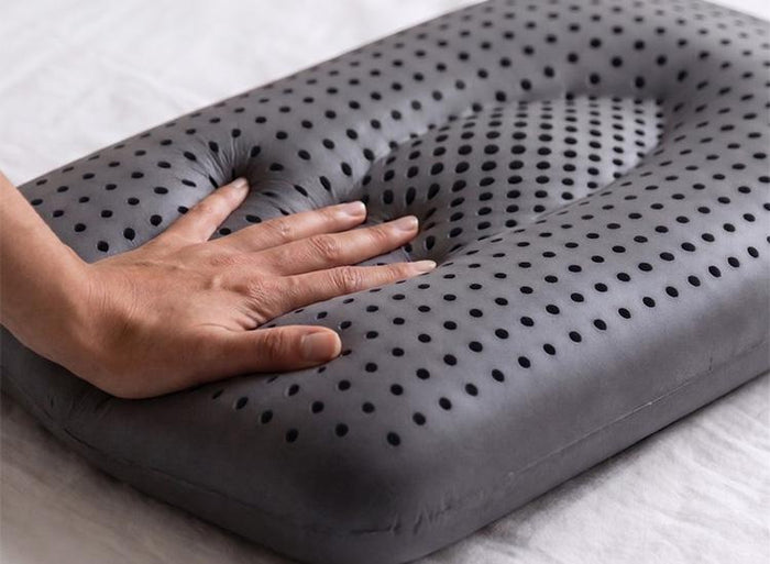 Hand resting on Turmerry Cooling Graphite Latex pillow surface.