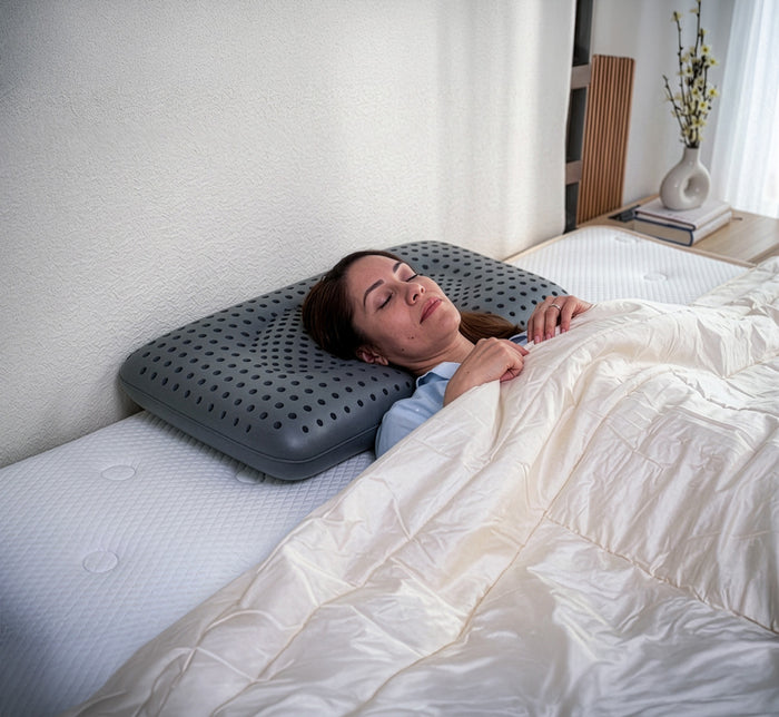 Woman with eyes closed sleeping peacefully on Turmerry Cooling Pillow in modern bedroom with cream bedding.