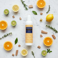 Jonathan Adler Citrus & Sandalwood Shampoo flat lay with citrus and sandalwood scent elements