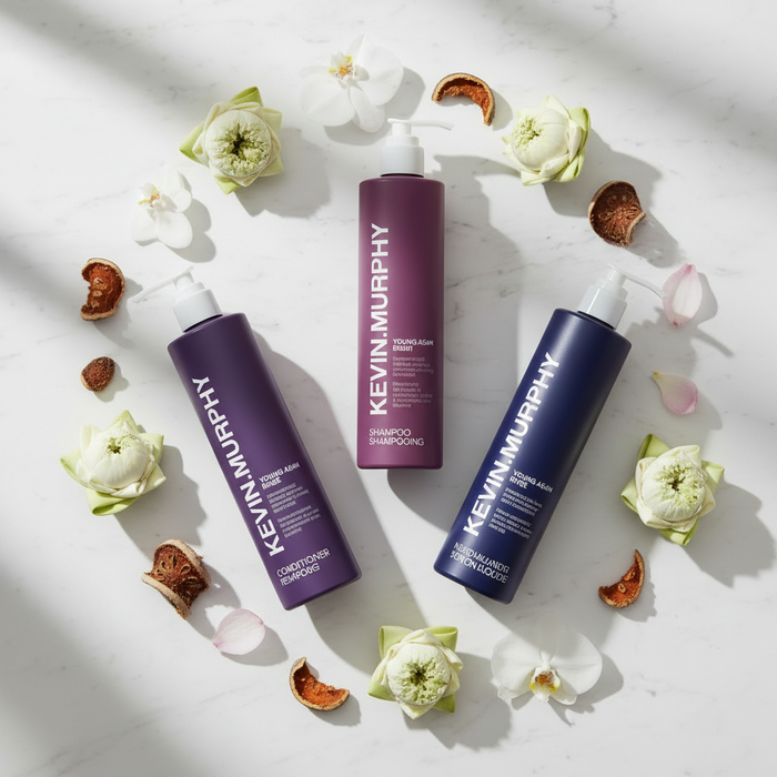 Kevin Murphy Young.Again 3-Piece Set flat lay with orchid blooms and lotus flowers on white marble — luxury hotel hair and body care bundle