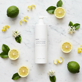 Korres Citrus Fresh Conditioner | 12.2 oz. surrounded by fresh citrus fruits on a marble surface.