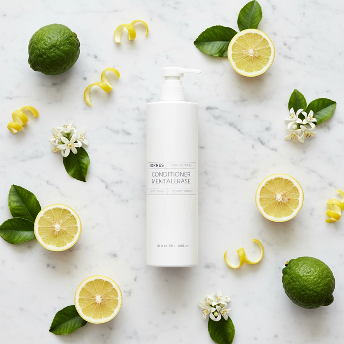 Korres Citrus Fresh Conditioner | 12.2 oz. surrounded by fresh citrus fruits on a marble surface.