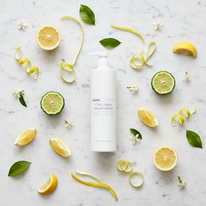 Korres Citrus Fresh Shampoo | 12.2 oz surrounded by citrus fruits and green leaves on a marble surface.