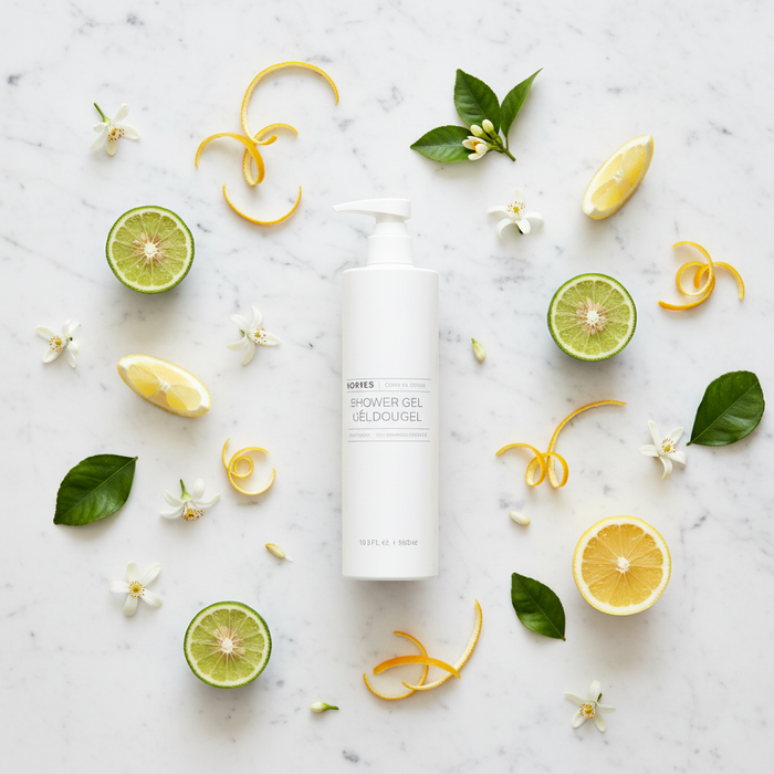 Korres Citrus Fresh Shower Gel | 12.2 oz. surrounded by citrus fruits and flowers on a marble surface.