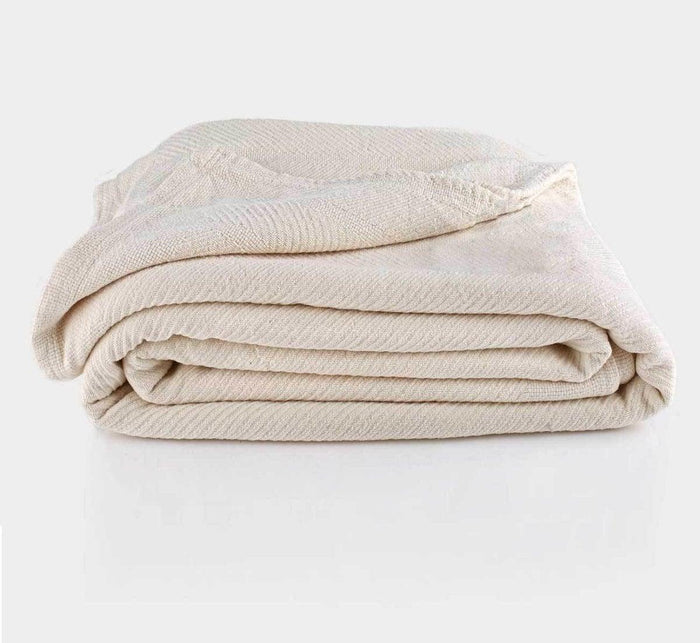 Cream-colored Turmerry Organic Chenille Herringbone Blanket Throw folded and placed on a light gray background.
