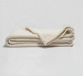Cream-colored Turmerry Organic Crepe Weave Blanket folded on a light gray background.