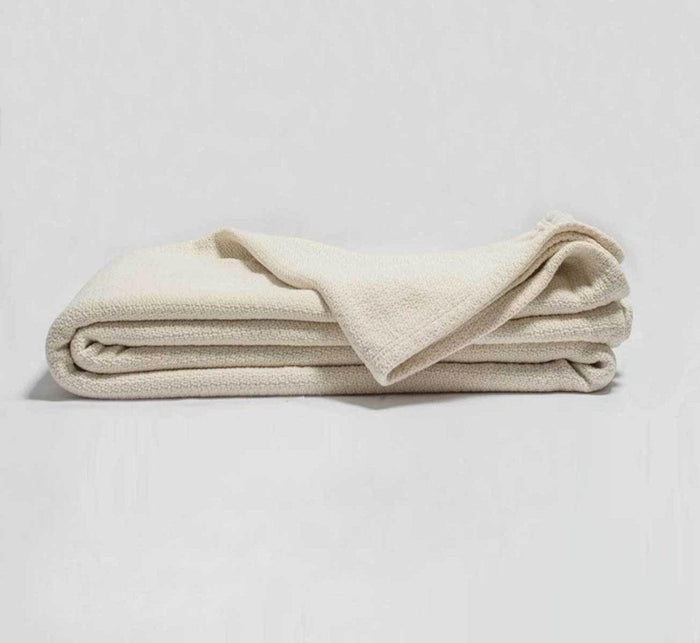 Cream-colored Turmerry Organic Crepe Weave Blanket folded on a light gray background.