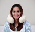 Woman wearing Turmerry latex travel neck pillow with white cover around neck against gray background.
