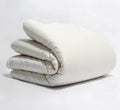 Turmerry Organic Sateen Duvet Cover put on a folded duvet, on a light gray background.