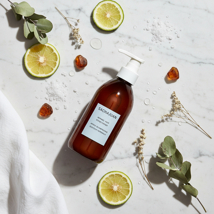 Sachajuan Hair Repair Conditioner flat lay with bergamot and botanicals on white marble