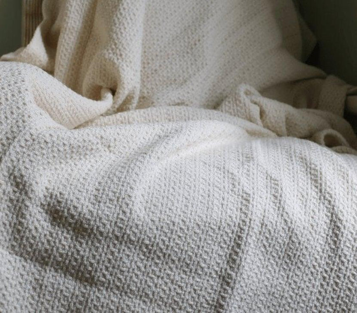 Turmerry Waffle Weave Organic Cotton Blanket Throw spread open on a bed, showing weave pattern.
